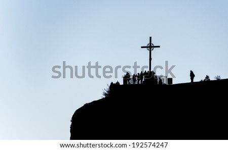 Montserrat, Spain - December 7, 2014: Silhouette image of the Cross on the cliff. Pilgrims come to pray at the cross.