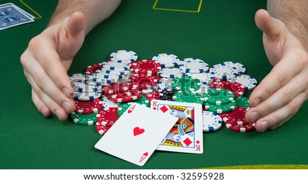 Hands racking in a a pile of poker chips with an ace king