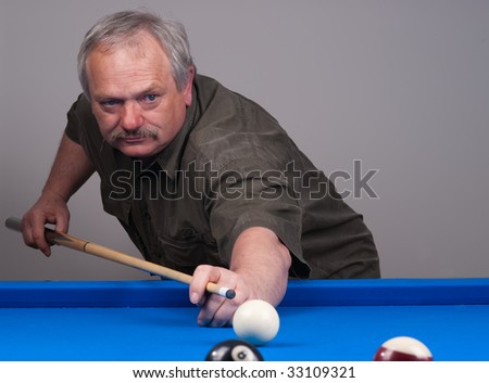 Man playing pool on blue felt billiard table and taking a shot with his cue.