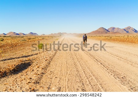 NamibRand Natural Reserve, Namibia - April 28, 2014: The man on the bicycle is cycling on the road C 27 in NamibRand Natural Reserve in Namibia.