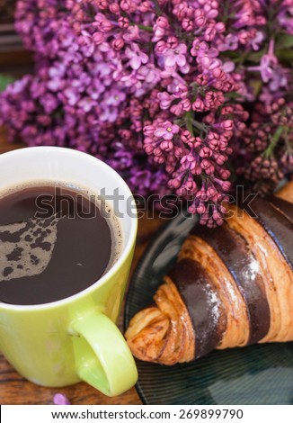 Coffee with lilac, croissant and good morning note on the wooden background