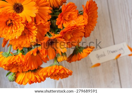 Orange flowers in a vase on a white wooden table with \