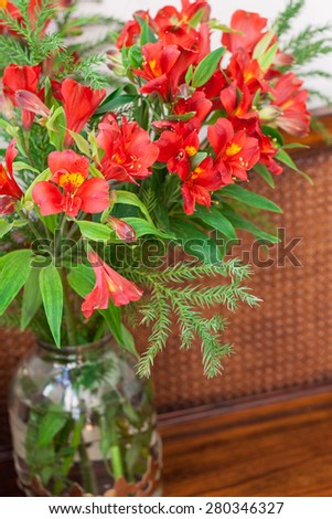 Red flowers in a vase on a wooden background