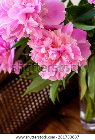 Pink peonies in the vase  on the wooden and straw bench