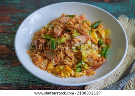 Nasi Goreng Sosis Indonesian Fried Rice with sausages on a white plate on the green wooden background Zdjęcia stock © 