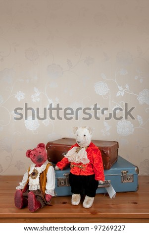 Two vintage teddy bears on wooden shelf with old suitcases. Space for text. Suitable for greeting cards.