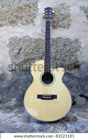 Acoustic guitar leaning against a stone wall with great colors