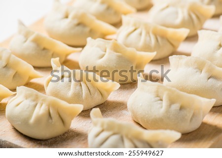 Raw Homemade Chinese Dumplings on Wooden Board