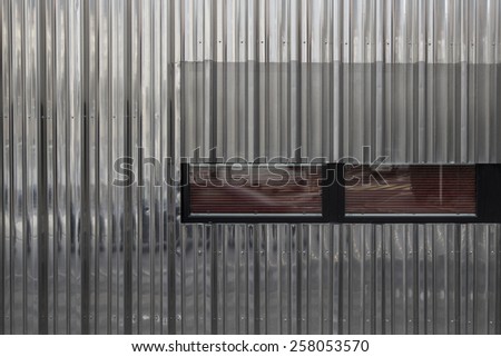 metal facade cutted by a black and red window frame