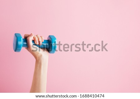 Womans hand holding blue dumbbell isolated on pink background. Equipment for home workout. Fitness and activity. Sport and healthy lifestyle concept. Copy space in right side Photo stock © 