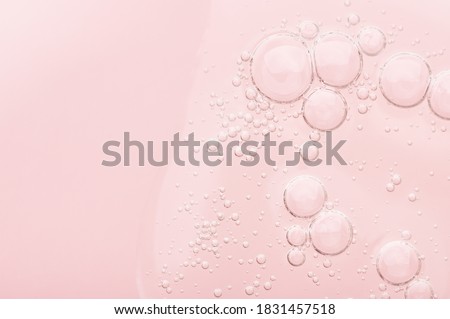 The texture of a liquid transparent gel for face cleansing. Sample of oil serum with bubbles on a pink background. Moisturizing cosmetic beauty product for skincare. Lotion for dry skin care