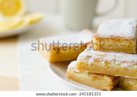 lemon bars on a white plate with slices of lemon