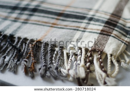 grey and brown checkered knitted folded blanket with fringe