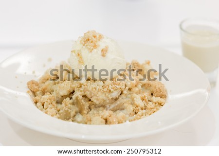 Apple crumble dessert with melted vanilla ice cream on the top.