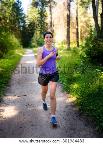 Girl in purple shirt runs into the woods. A healthy lifestyle. Training for a marathon.