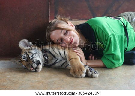 TIGER TEMPLE, THAILAND - February, 2012: girl sleeps on the cute baby tiger.