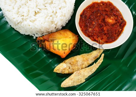 Malaysian traditional food Nasi Lemak served with spicy shrimp gravy, salted fish and fried chicken on banana leaf plate.