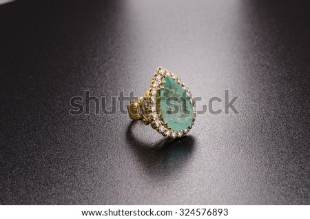yellow gold ring with emerald and diamonds isolated on black background