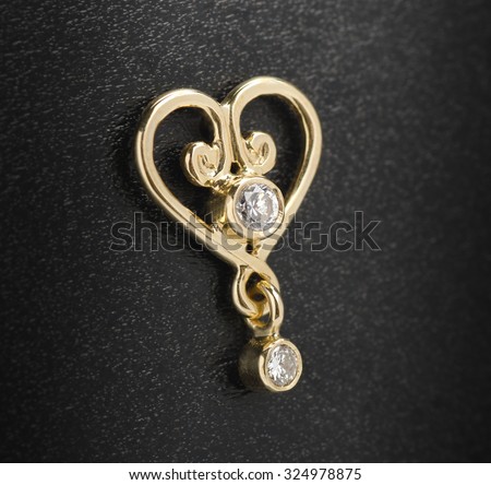 heart gold earrings with diamonds isolated on a black background