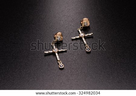 cruciform gold earrings and pendant with diamonds isolated on a black background
