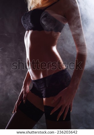 Smoking hot sexy female body in black lingerie and stockings on dark background