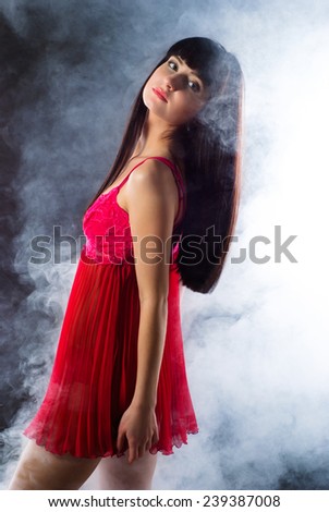 Portrait of a smoking hot sexy fit young woman posing in pink peignoir on dark background