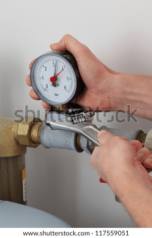Man\'s hands screwing pressure gauge with wrench