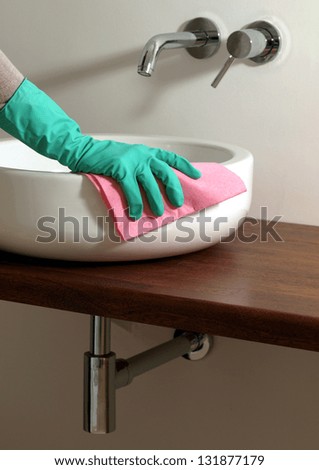 Hand cleaning bathroom sink with glove and rubber
