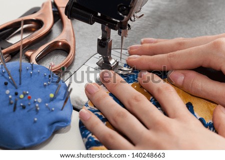 Woman\'s hands with dress at sewing machine