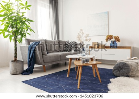 Flowers on wooden coffee table in fashionable living room interior with scandinavian design