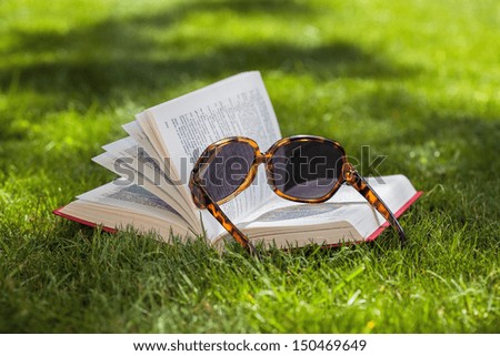 Book and sunglasses on a green grass