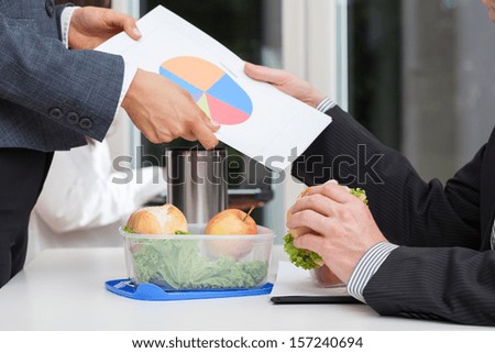 Managers analyzing a pie chart during a lunch at the desk