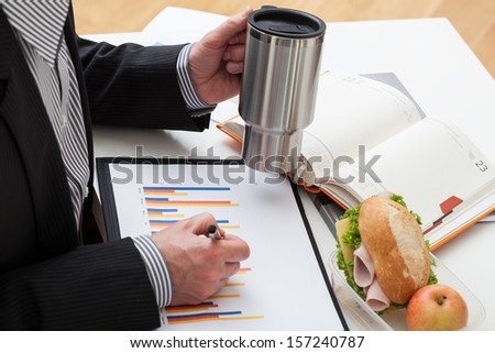 Busy businessman with mug and homemade sandwiches