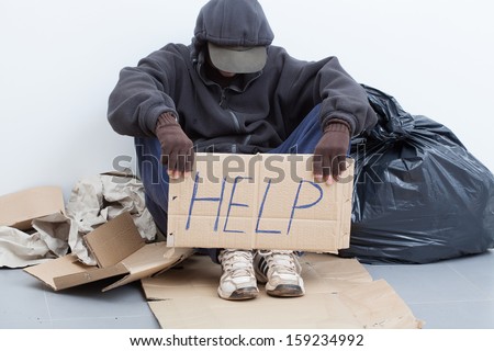 Homeless man sitting on a street with sign