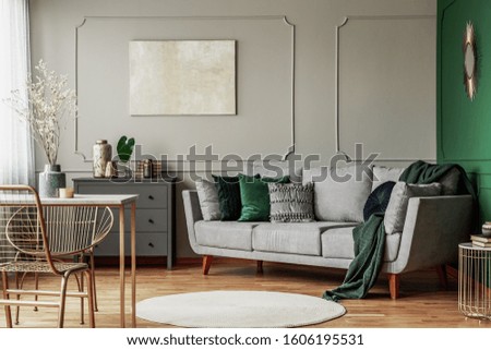 Stylish emerald green and grey living room interior design with abstract painting on the wall