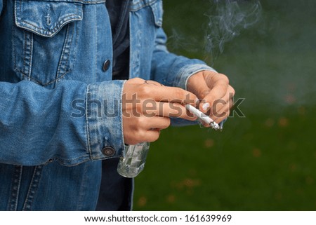 Teenager smoking a cigarette and drinking vodka from the bottle