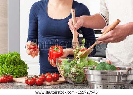 Couple cooperating in kitchen during making salad