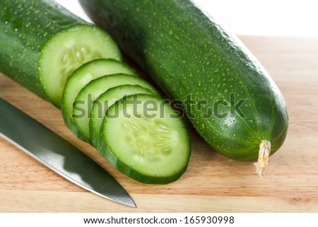 Two cucumbers cut into slices and a silver knife