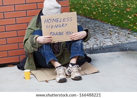 Homeless with cardboard on his neck drinking hot tea