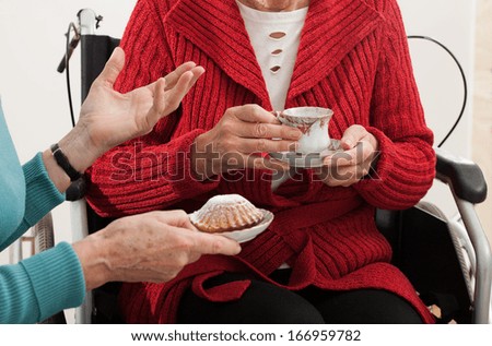 Elder woman on wheelchair has a nice friend visit for coffee and cake