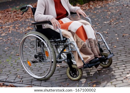 Old person sitting on wheelchair outdoor in autumn