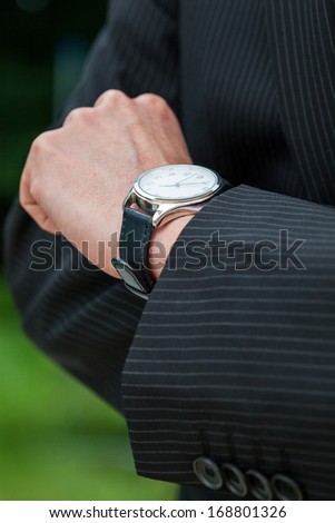 Man in suit checking the time on designer watch