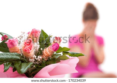 A closeup of a bouquet of roses with an unhappy woman in the background