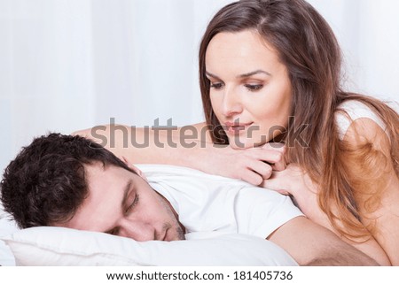Sleeping man and pretty awake woman in bed