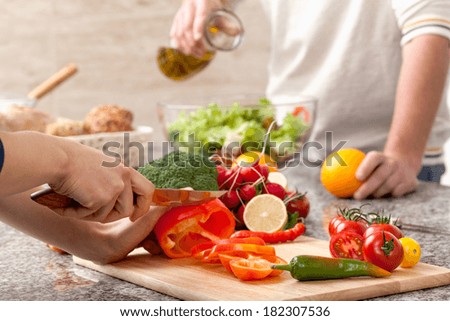 Cutting a vegetables for a salad with an olive oil