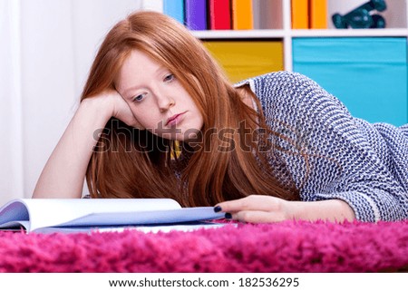 Teenage girl lying in her room and studying hard