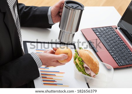 Office worker who are eating sandwich and apple during the work