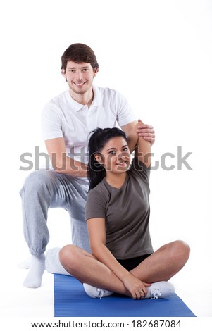 A young woman stretching with her handsome personal trainer