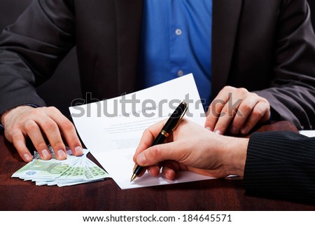 A closeup of a man signing an express cash loan agreement