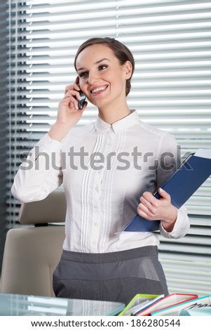 Beautiful secretary talking at the phone and smiling